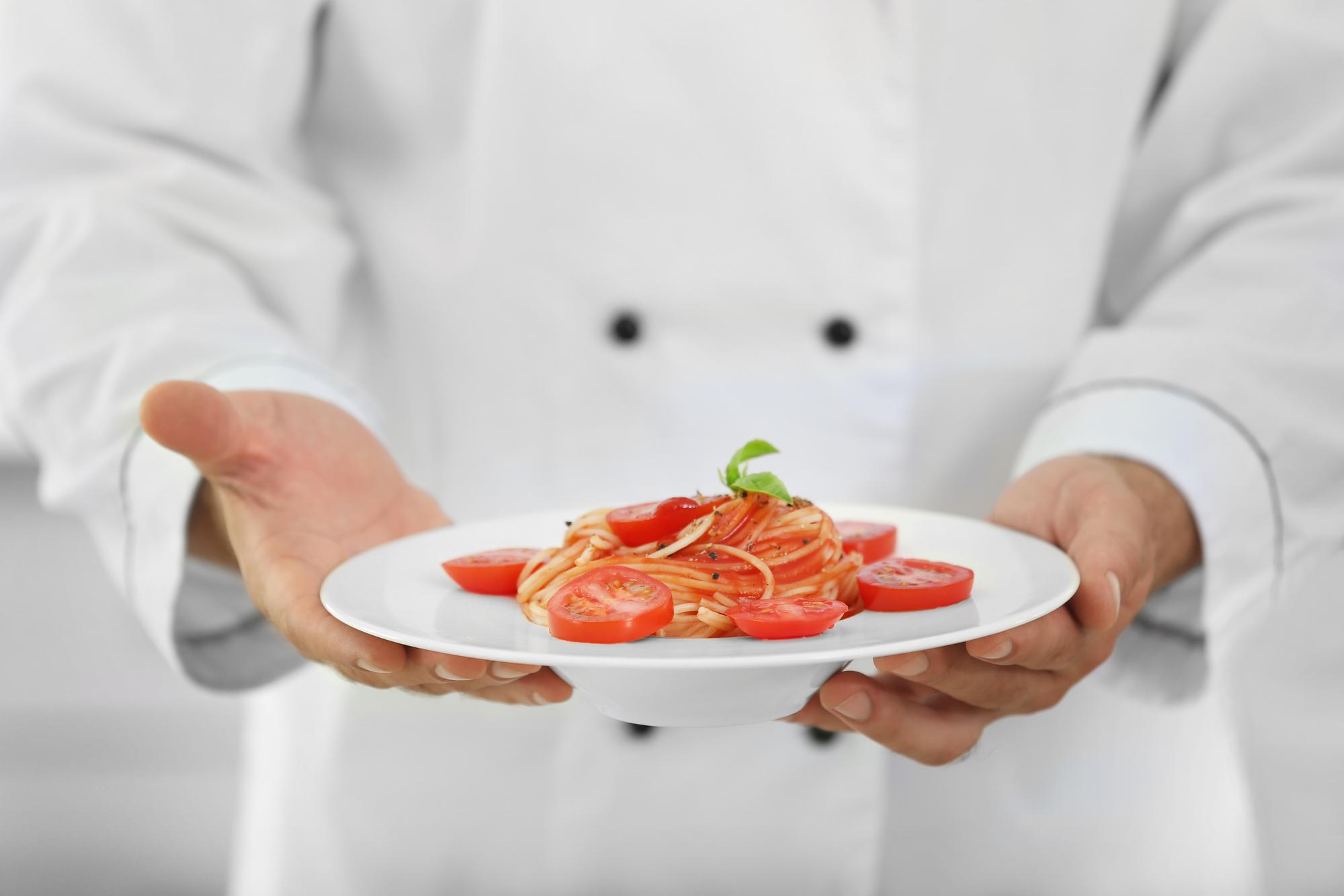 chef plating a modern dish on a wooden table